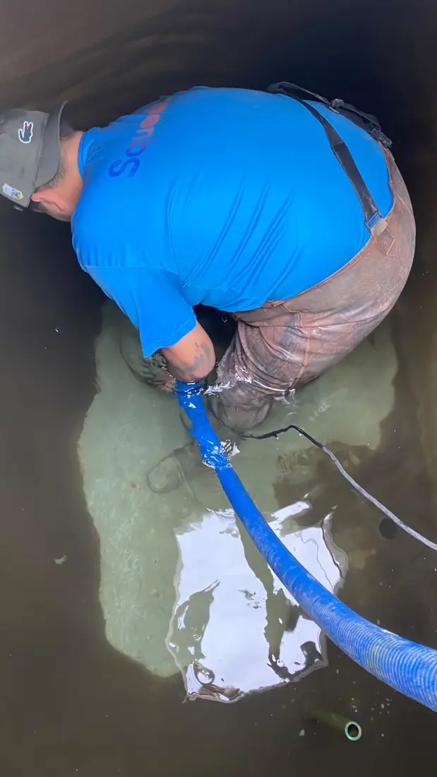 Técnico da D.Lucca drenando reservatório de água de condomínio durante a limpeza